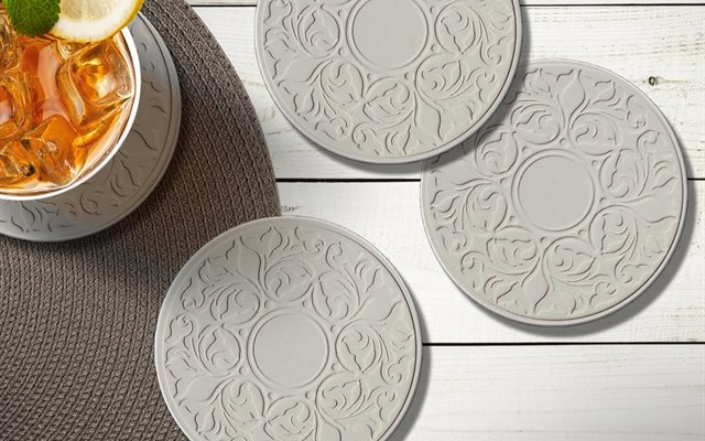 Embossed Victorian Lace coasters on a white tstable with iced tea